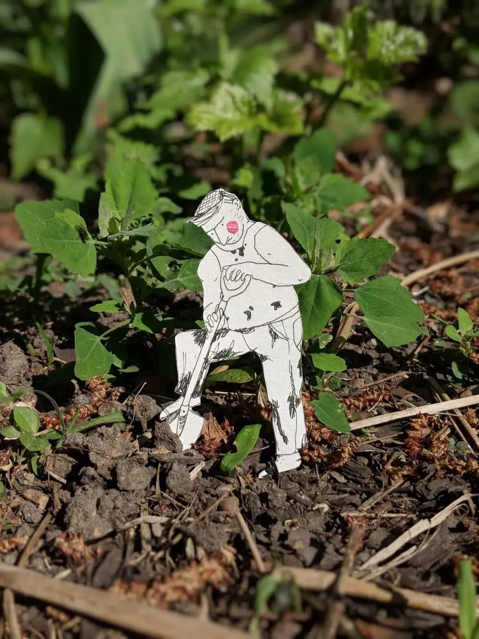 Cut-out gardener in a flat cap leaning on a spade in sunlit soil between green seedlings