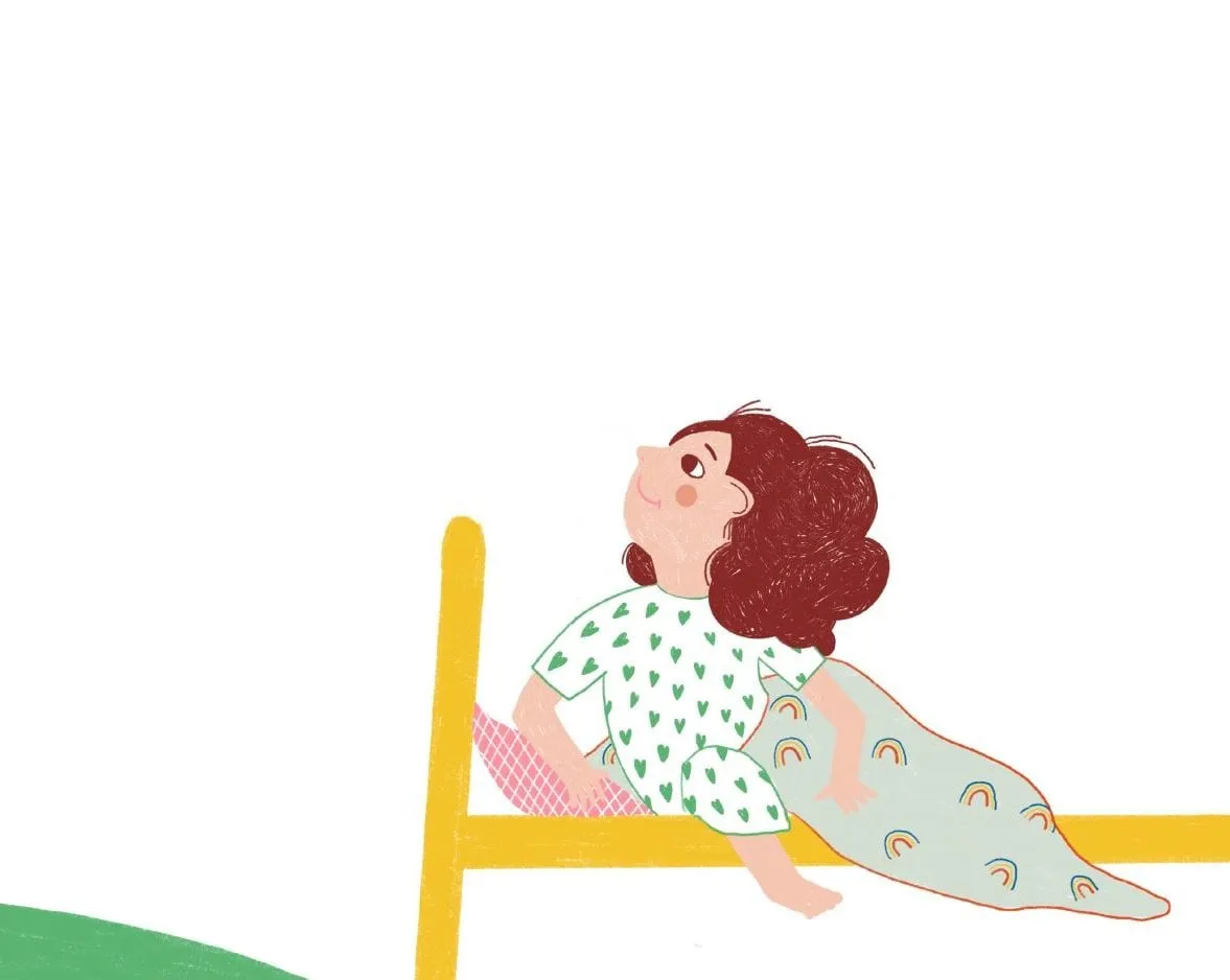 Girl in heart-print pyjamas kneels at the foot of a yellow bed, rainbow blanket trailing