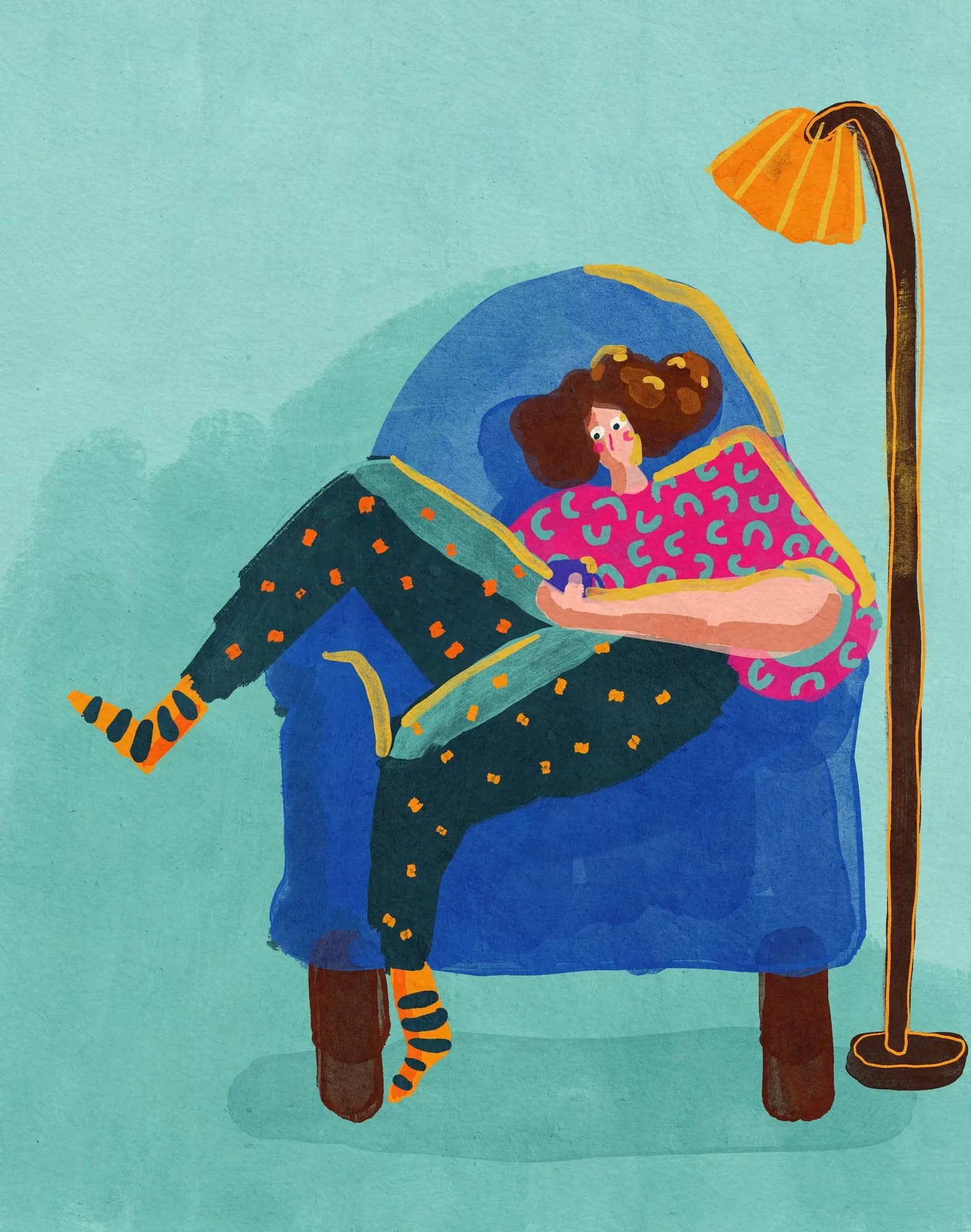 Woman curled sideways in a big blue armchair under an orange floor lamp, absorbed in what she holds